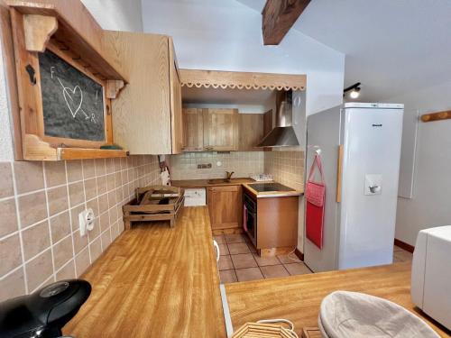 une cuisine avec des placards en bois et un tableau noir sur le mur dans l'établissement Spacieux appartement 8 personnes au pied des pistes avec parking et WiFi - FR-1-505-179, à Notre-Dame-de-Bellecombe
