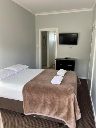 a bedroom with a bed with two towels on it at Restawile Motel in Busselton