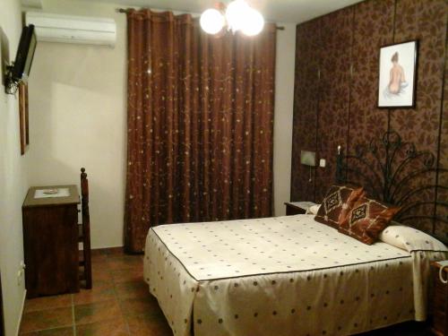 a bedroom with a bed and a window with curtains at Hostal Piñera in Vega de Espinareda