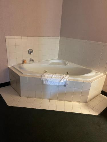 y baño alicatado con bañera blanca. en Red Carpet Inn Macon East, en Macon