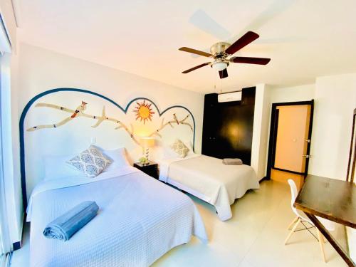 een slaapkamer met twee bedden en een plafondventilator bij VIA TENDENZA VILLAS in Playa del Carmen