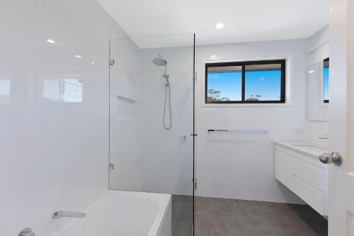 a white bathroom with a shower and a sink at Lakeside Tranquillity in The Entrance