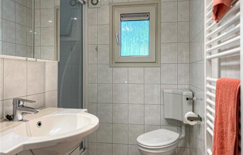 een badkamer met een wastafel, een toilet en een raam bij Amazing Home In Vorden With Kitchen in Vorden
