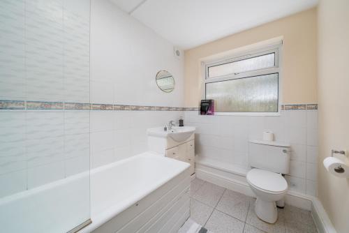 a white bathroom with a tub and a toilet at Redhill Surrey 2 Bedroom Pet Friendly Apartment by Sublime Stays in Redhill