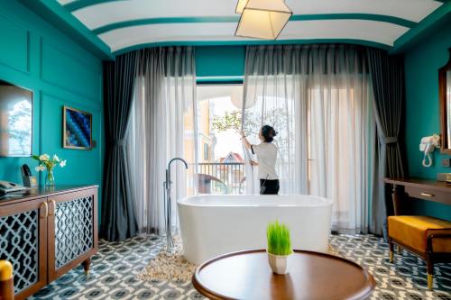 a woman standing in a bathroom with a bath tub at Son Hoi An Boutique Hotel & Spa in Hoi An