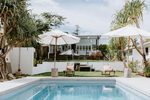 a house with a swimming pool and two umbrellas at Yeppoon Surfside Motel in Yeppoon