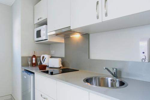 a kitchen with white cabinets and a sink at Voile Bleue Boutique Hotel in Trou aux Biches