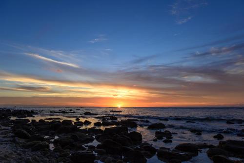 a sunset on a beach with rocks in the water at Voile Bleue Boutique Hotel in Trou aux Biches