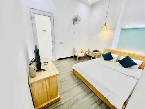 a bedroom with a bed and a desk with a tv at D'Villa Hotel - Homestay in Kon Tum