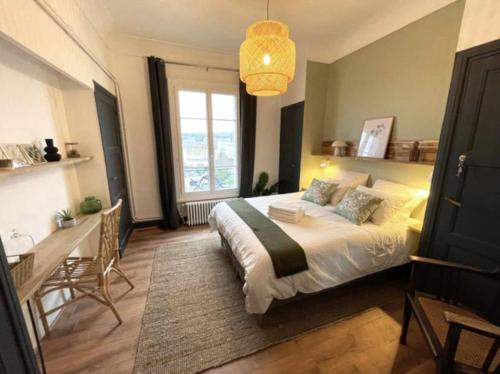 1 dormitorio con cama, escritorio y ventana en Vichy : Le 5e - Appartement design dans un ancien palace en Vichy