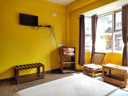 Camera gialla con TV su una parete gialla di Hotel Mhelung a Darjeeling