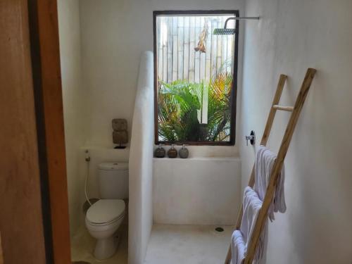 a bathroom with a toilet and a window at Sal Central in Uluwatu