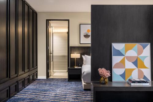 a bedroom with a bed and a table with a painting at Kimpton Margot Sydney, an IHG Hotel in Sydney