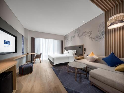 ein Hotelzimmer mit einem Bett und einem Sofa in der Unterkunft Holiday Inn Express Tengchong Hot-Spring, an IHG Hotel in Tengchong