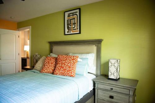 Charming vacation home in Port St Lucie. في بورت سانت لوسي: غرفة نوم مع سرير مع وسائد برتقالية وموقف ليلي