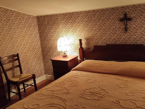 ein Schlafzimmer mit einem Bett und einem Stuhl sowie einem Kreuz an der Wand in der Unterkunft Nice villa in Ragalna with a nice garden in Ragalna
