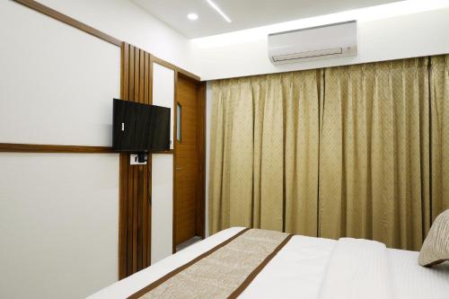 スーラトにあるTulsi Hotelのベッドとテレビがあるホテルの部屋
