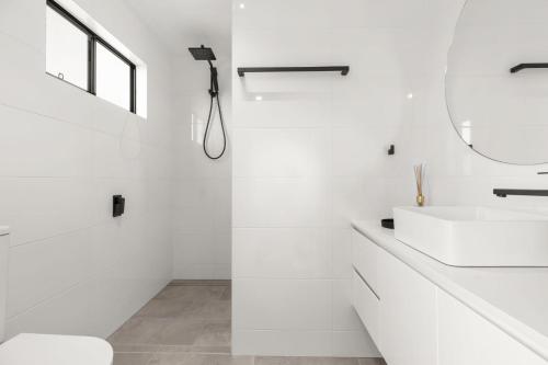 a white bathroom with a sink and a mirror at Bella Vita by Experience Jervis Bay in Vincentia