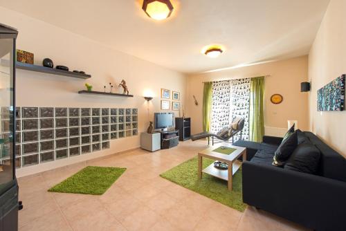 a living room with a black couch and a tv at Olive Private Villa Swimming Pool 5 BDR Kolymbia Rhodes in Kolimbia