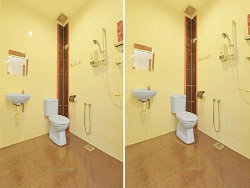 two toilets in a bathroom with a sink at OYO 582 Hotel Walk Inn in Melaka