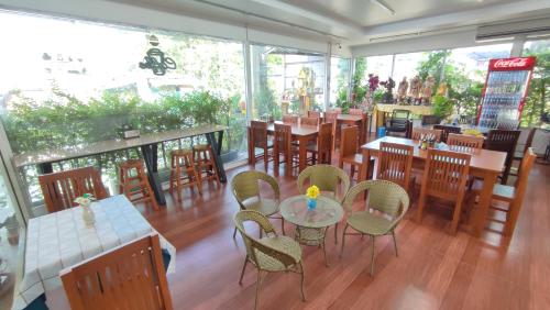 a restaurant with wooden tables and chairs and windows at Pa Chalermchai Guesthouse in Bangkok