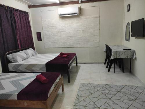 a bedroom with two beds and a table and a desk at CiTY Roomstay Budget Midtown Kuala Terengganu 2queen beds in Kuala Terengganu