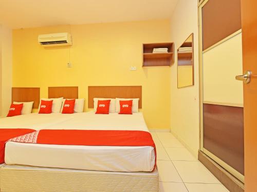 1 dormitorio con 1 cama grande con almohadas rojas en OYO 582 Hotel Walk Inn, en Melaka