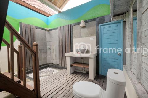 a bathroom with a toilet and a blue door at Dream Beach Kubu & SPA by ABM in Nusa Lembongan