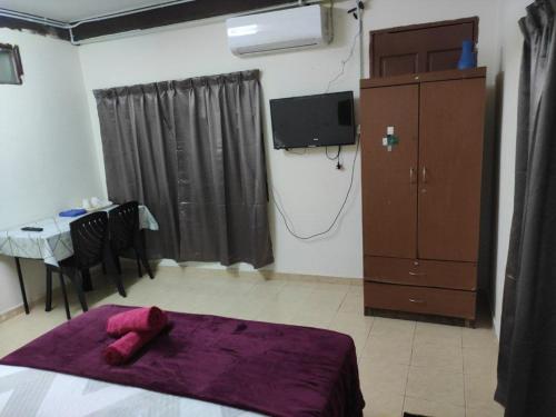 a bedroom with a bed with a purple blanket and a table at CiTY Roomstay Budget Middle Kuala Terengganu 1queen bed in Kuala Terengganu