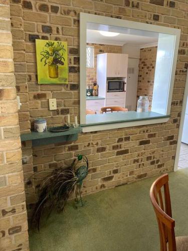 a bird on a brick wall with a mirror at Crescent Head - Killick Glen - a couple's retreat in Crescent Head