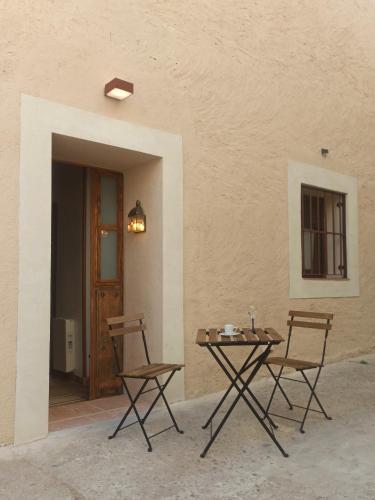 une table et deux chaises assises à côté d'un mur dans l'établissement Casa Rural Casona Camino Pedraza - 4 Estrellas, à Arcones