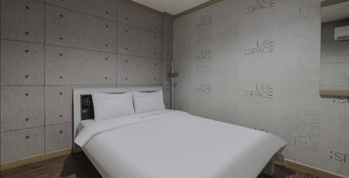 a white bed in a room with writing on the wall at Queen Motel Andong in Andong