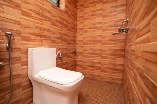 a bathroom with a toilet and wooden walls at TM Calangute House Stay at Goa in Calangute
