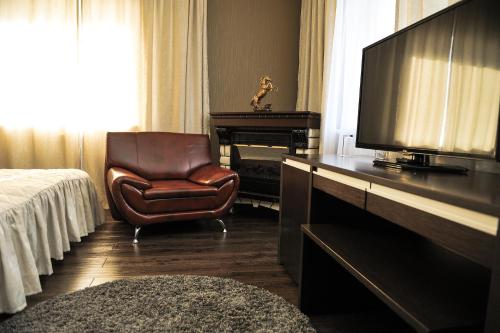 a bedroom with a bed and a chair and a television at Hotel Svetofor in Lgov