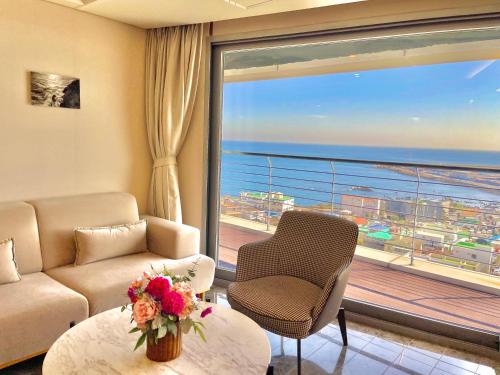 a living room with a couch and a large window at Hotel bridge Seogwipo in Seogwipo
