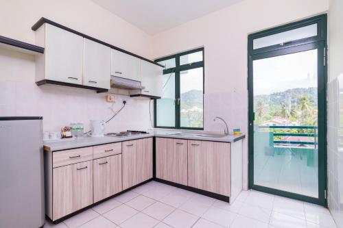 a kitchen with wooden cabinets and a large window at HIG Homestay Apartment in Kuah
