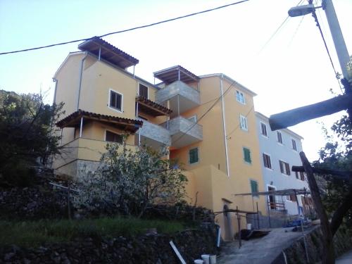 a large yellow and white building on a hill at Apartments by the sea Valun, Cres - 8086 in Valun