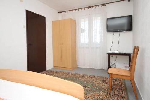 a bedroom with a bed and a tv and a chair at Apartment Verunic 8104a in Veli Rat