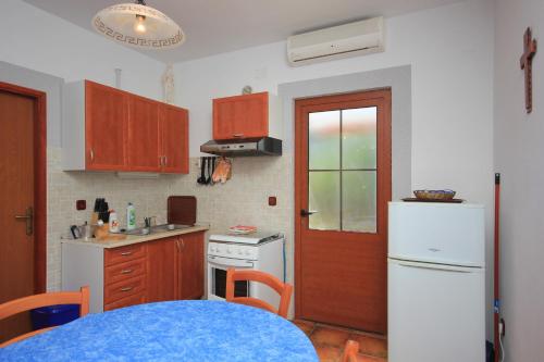 a kitchen with a white refrigerator and a red door at Apartments by the sea Ilovik, Losinj - 8075 in Ilovik