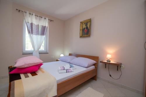 ein Schlafzimmer mit einem Bett mit zwei Kissen und einem Fenster in der Unterkunft Apartments with a parking space Punta kriza, Cres - 8082 in Punta Križa