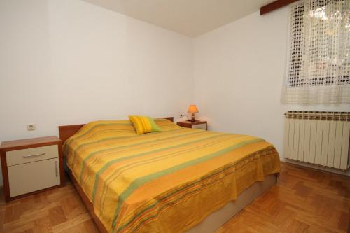 a bedroom with a large bed with a yellow blanket at Apartment Mali Losinj 8090c in Mali Lošinj