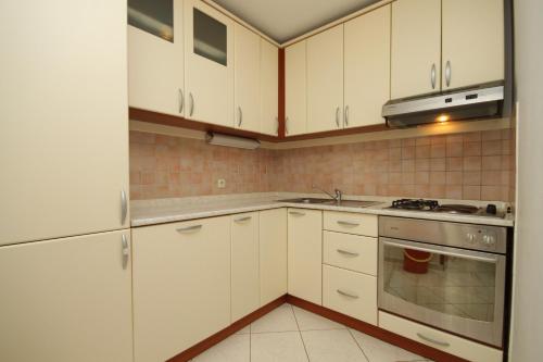 a kitchen with white cabinets and a stove top oven at Apartment Mali Losinj 8090c in Mali Lošinj