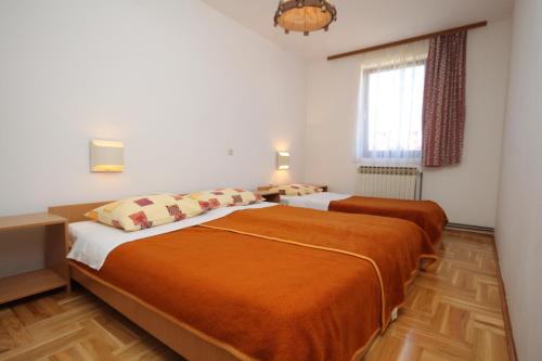 two beds in a room with white walls and wooden floors at Apartments with a parking space Mali Losinj (Losinj) - 8090 in Mali Lošinj