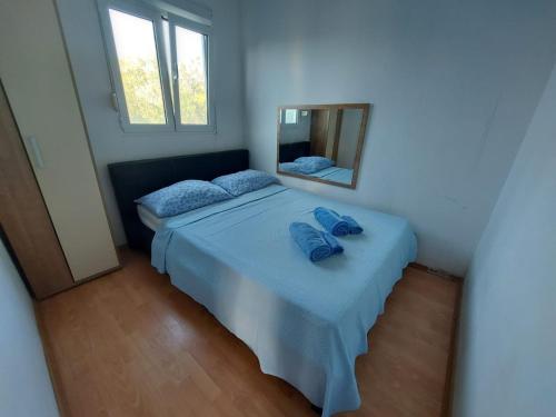 a bedroom with a bed with blue sheets and a mirror at Secluded fisherman's cottage Krknata, Dugi otok - 8150 in Zaglav