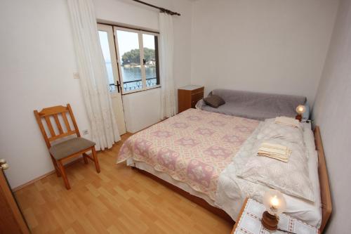 - une chambre avec un lit, une chaise et une fenêtre dans l'établissement Apartment Savar 8079a, à Brbinj