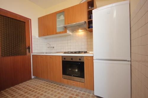 eine Küche mit einem weißen Kühlschrank und Holzschränken in der Unterkunft Apartments by the sea Savar, Dugi otok - 8080 in Brbinj