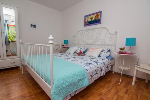 a bedroom with a white bed with a blue comforter at Apartments by the sea Mali Losinj (Losinj) - 8093 in Mali Lošinj