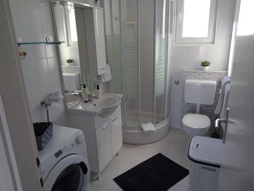 a white bathroom with a sink and a washing machine at Apartments with a parking space Sali, Dugi otok - 8154 in Sali