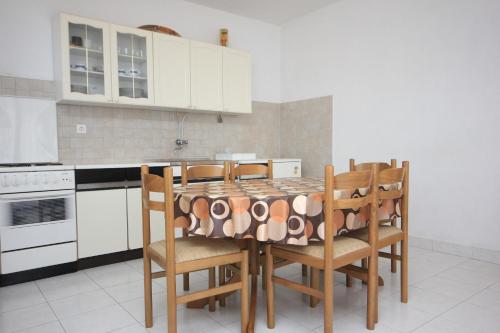 eine Küche mit einem Tisch mit Stühlen und weißen Schränken in der Unterkunft Apartment Sali 8121a in Sali