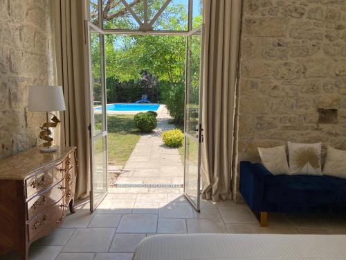 un salon avec une porte ouverte sur une piscine dans l'établissement Jas de Berrias Chambre d’hôte, à Berrias Et Casteljau